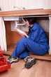 Young woman plumber fitting the waste on a kitchen sink