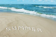 sandy beach with a word "Summer" written with seashells