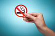 Photo: woman's hand holding a symbol - no smoking. Against blue backgro woman's hand holding a symbol - no smoking. Against blue backgro
