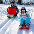 Happy winter - young girls  sledging downhill