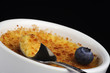 Closeup of a bowl of creme brulee with a blueberry