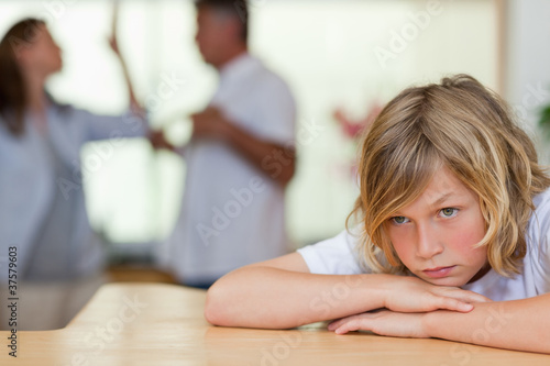 Photo: Worried looking boy with fighting parents behind him Worried looking boy with fighting parents behind him