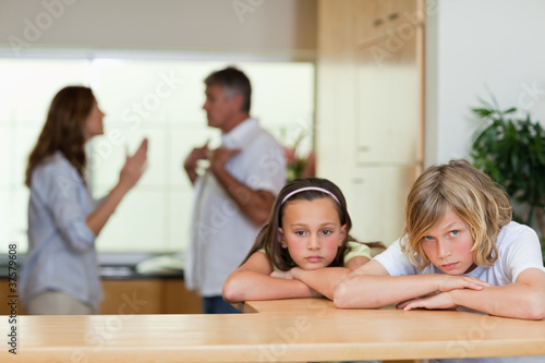 Photo: Sad looking siblings with arguing parents behind them Sad looking siblings with arguing parents behind them