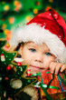 Photo: Happy small girl in santa hat with lot of gift have a christmas Happy small girl in santa hat with lot of gift have a christmas