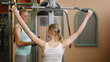 Fitness trainer explaining lat machine in gym