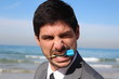 Young handsome businessman with a blue dart in his mouth