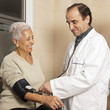 Doctor measuring blood pressure of senior patient at hospital