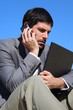 A businessman is talking on his smartphone outdoor