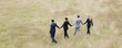 Business people holding hands walking in field