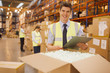 Worker with laptop checking box in warehouse