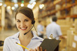 Woman in headset holding clipboard in warehouse
