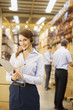 Businesswoman with clipboard working in warehouse