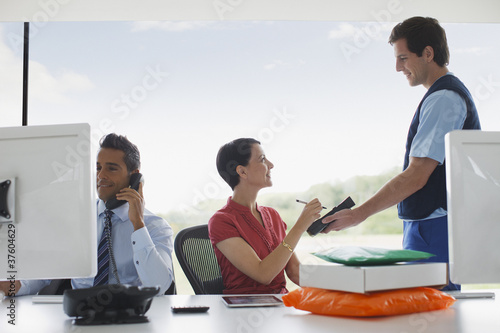 Foto: Businesswoman signing for package in office Businesswoman signing for package in office