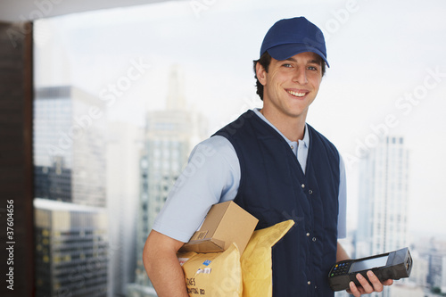 Photo: Deliveryman carrying packages and electronic device Deliveryman carrying packages and electronic device