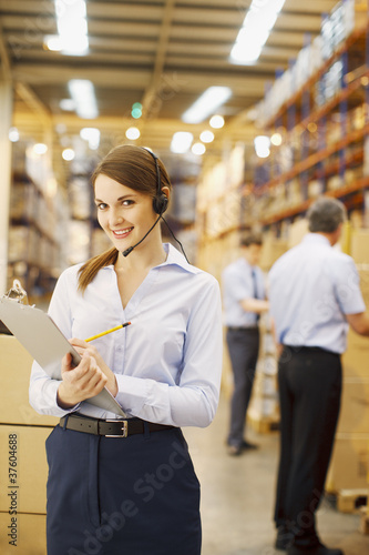 Photo: Businesswoman with clipboard working in warehouse Businesswoman with clipboard working in warehouse
