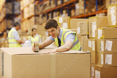Photo: Worker taping box in warehouse Worker taping box in warehouse