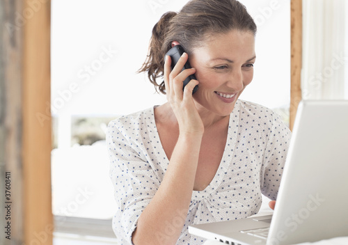 Foto: Woman using laptop and talking on cell phone Woman using laptop and talking on cell phone