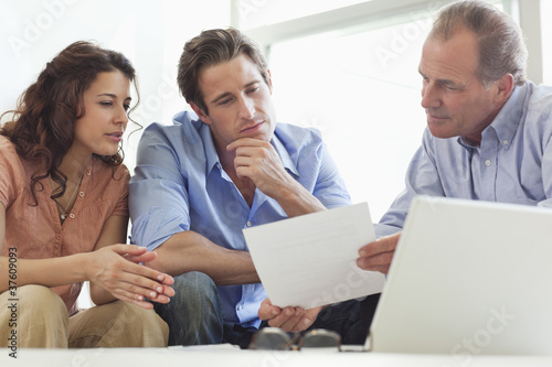 Photo: Couple going over paperwork with financial advisor Couple going over paperwork with financial advisor