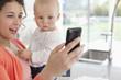 Foto: Mother holding baby and using cell phone Mother holding baby and using cell phone
