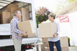 Couple unloading boxes from moving van