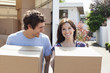 Couple unloading boxes from moving van
