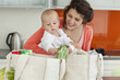 Mother holding baby and unloading groceries