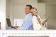 Couple in bedroom using laptop and digital tablet