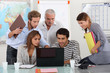 Students and teacher gathered around laptop computer