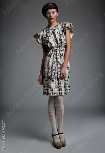 Photo: Fashion model in retro dress standing in studio Fashion model in retro dress standing in studio