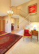 Photo: Luxury entrance living room with red rug, staircase. Luxury entrance living room with red rug, staircase.