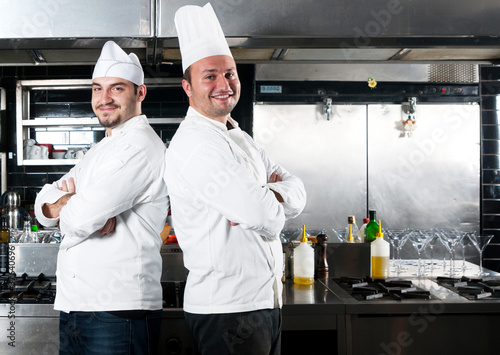 Photo: Portrait of two chefs smiling and holding kitchen utensil Portrait of two chefs smiling and holding kitchen utensil