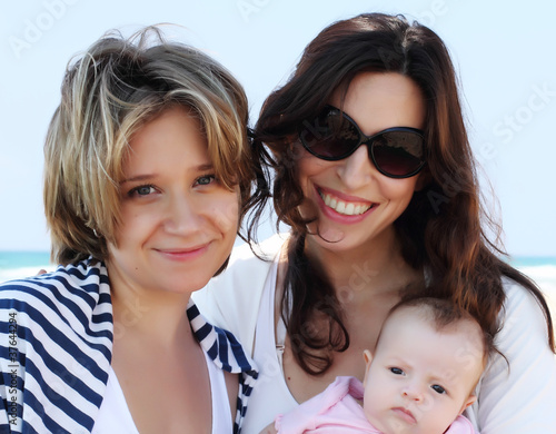 Photo: two beautiful girls with a baby on the beach two beautiful girls with a baby on the beach