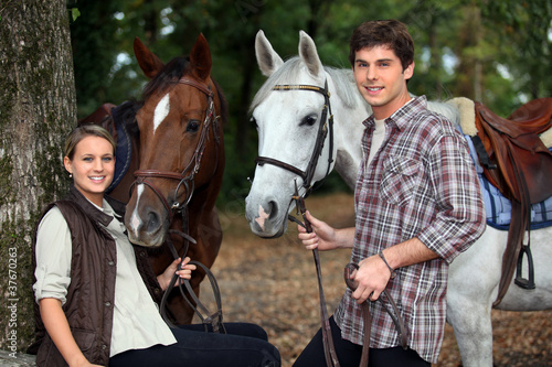 Photo: young couple and horses in forest young couple and horses in forest