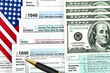 Tax forms with pen, money and U.S. flag.