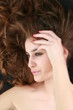 Young beautiful woman with curly hair on black background