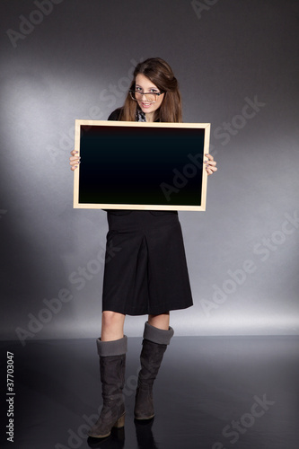 Foto: Junge Dame mit Tafel präsentiert und lächelt Junge Dame mit Tafel präsentiert und lächelt