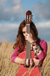 girl hiding behind a guitar in corn field