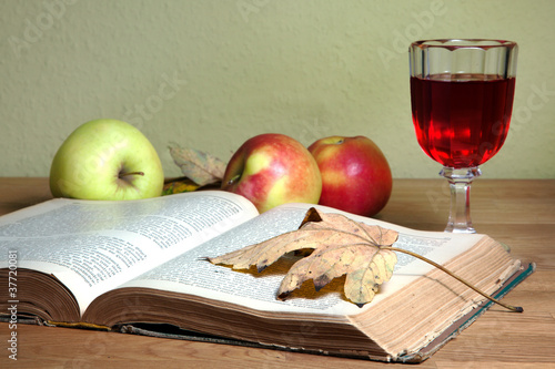 Photo: Offenes altes Buch mit Herbstlaub und Rotweinglas Offenes altes Buch mit Herbstlaub und Rotweinglas