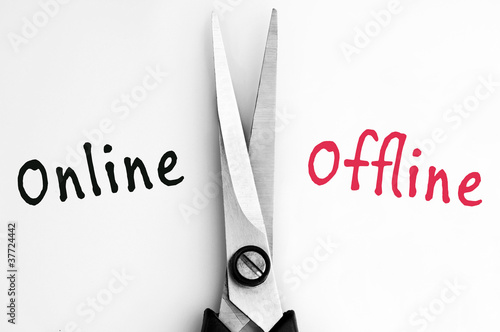 Photo: Online and Offline words with scissors in middle Online and Offline words with scissors in middle