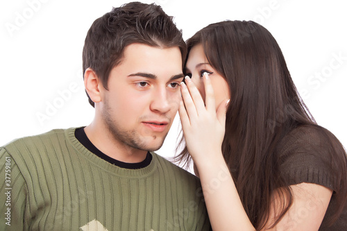 Photo: Portrait of young woman telling a secret to a man over a white b Portrait of young woman telling a secret to a man over a white b