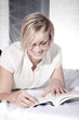 Junge Frau liest begeisternd ein Buch und lacht