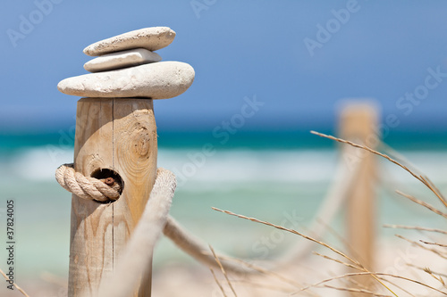 Photo: Stones balanced on wooden banister near the beach. Stones balanced on wooden banister near the beach.