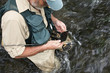 Fly fisherman holding fly box in river Fly fisherman holding fly box in river