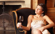 woman with a glass of red wine at a fireplace