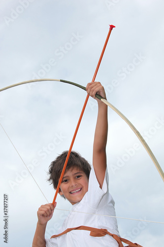 Photo: Happy little boy playing with bow and arrow Happy little boy playing with bow and arrow