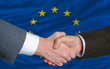 businessmen handshake after good deal in front of europe flag businessmen handshake after good deal in front of europe flag