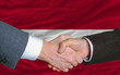 businessmen handshake after good deal in front of latvia flag