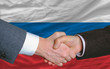 businessmen handshake after good deal in front of russia flag