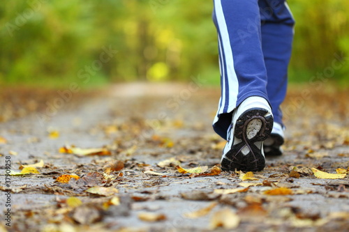 Photo: Woman walking cross country trail in autumn forest Woman walking cross country trail in autumn forest