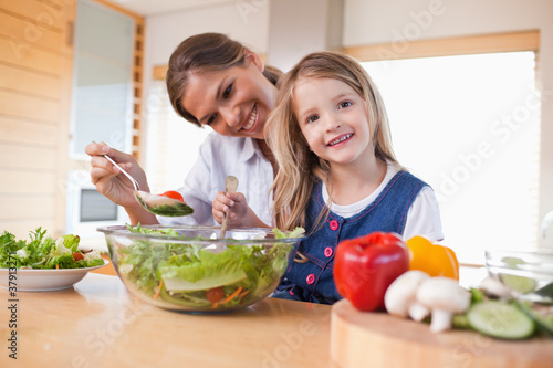 Photo: Happy mother and her daughter preparing a salad Happy mother and her daughter preparing a salad
